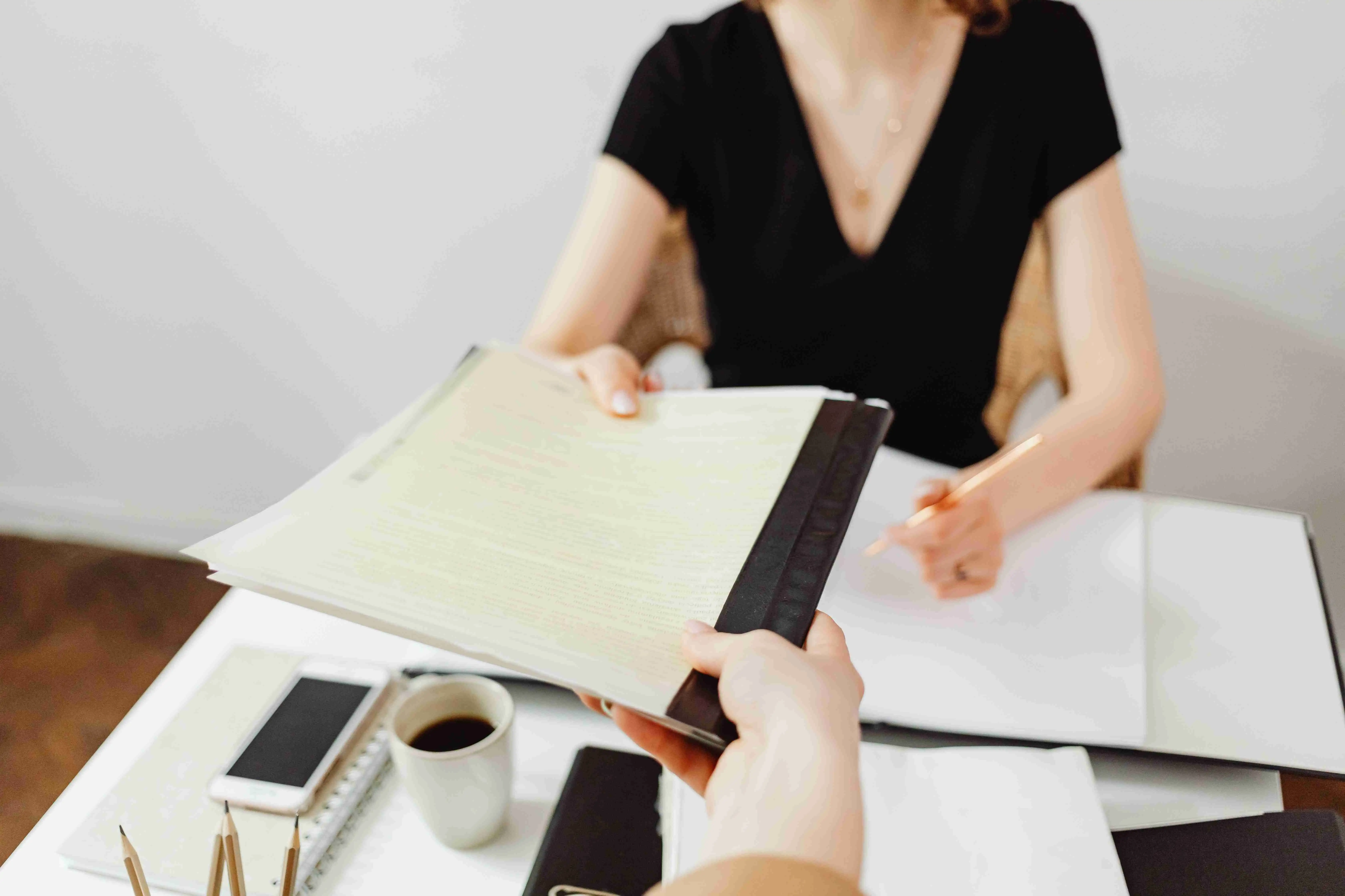 A business expert organizing files and documents on a white desk