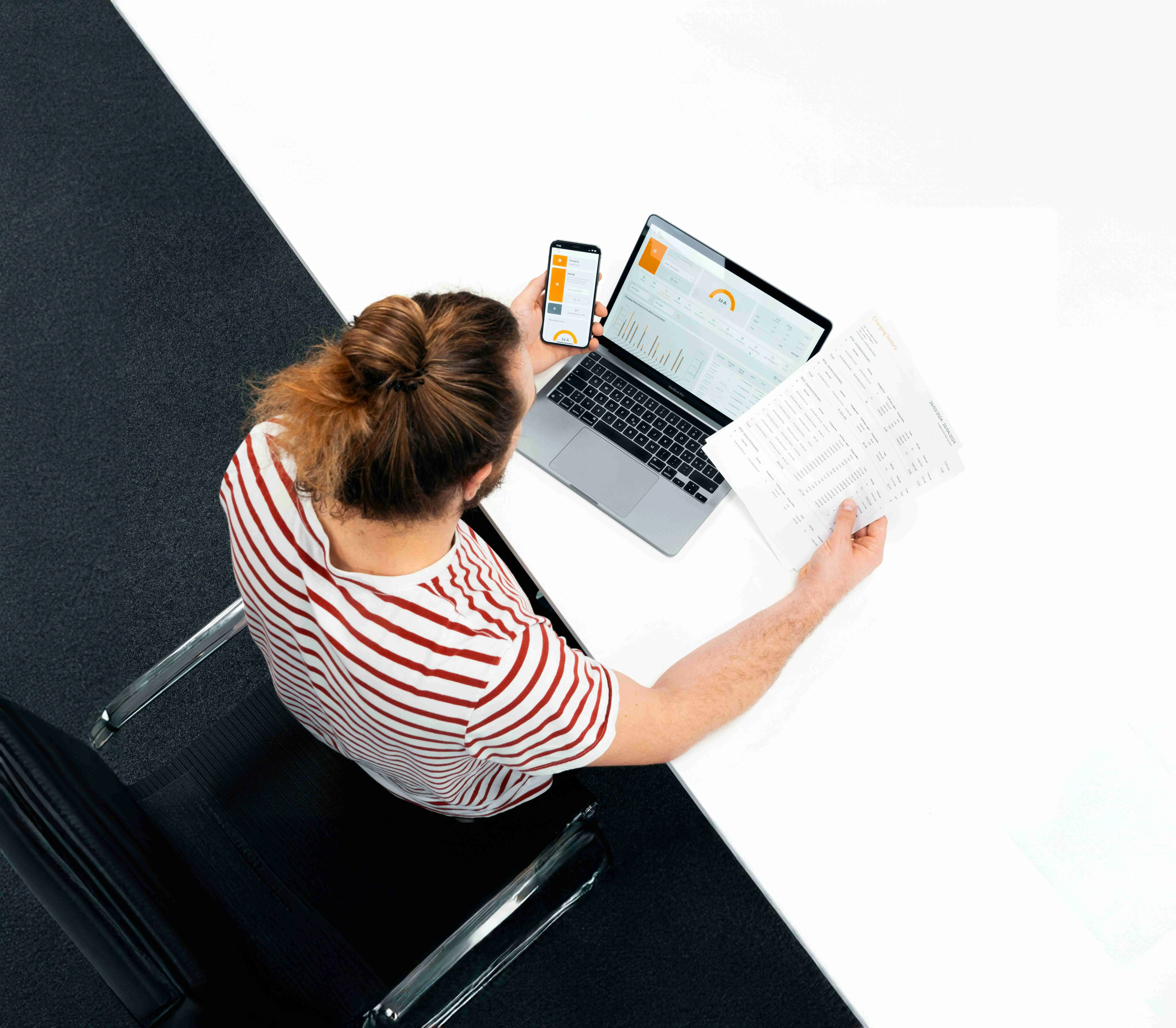 Top-down view of a woman working on a laptop with documents