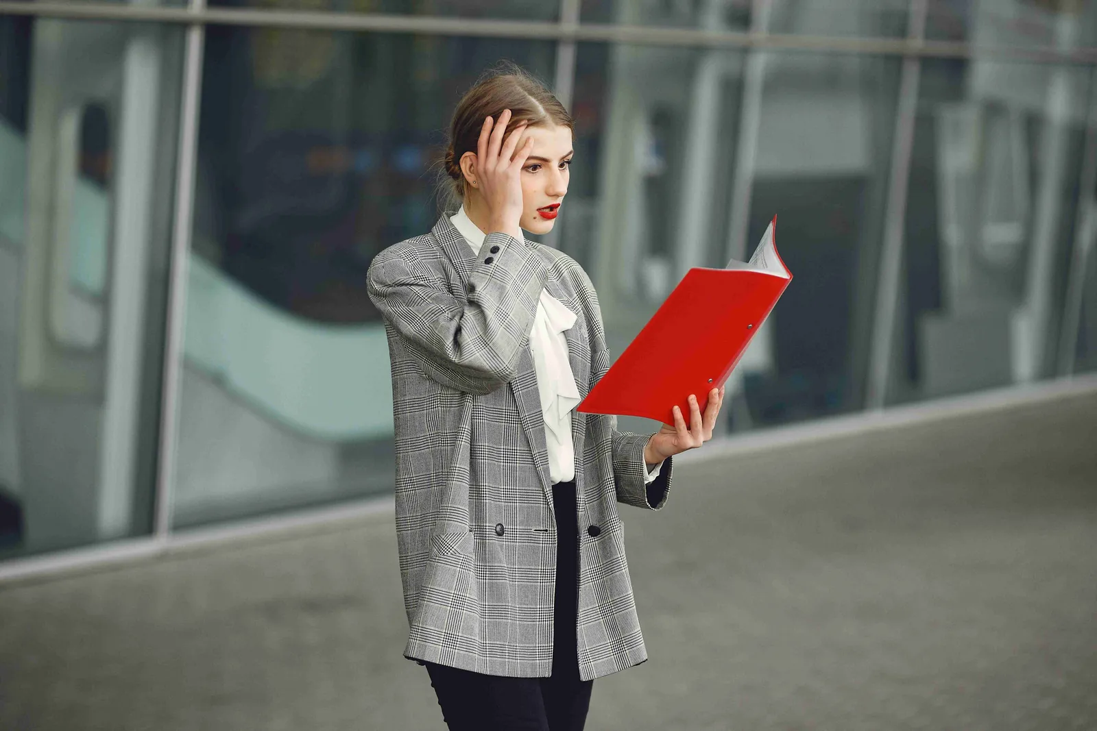 A businesswoman wearing a mask and holding a red folder at an airport
