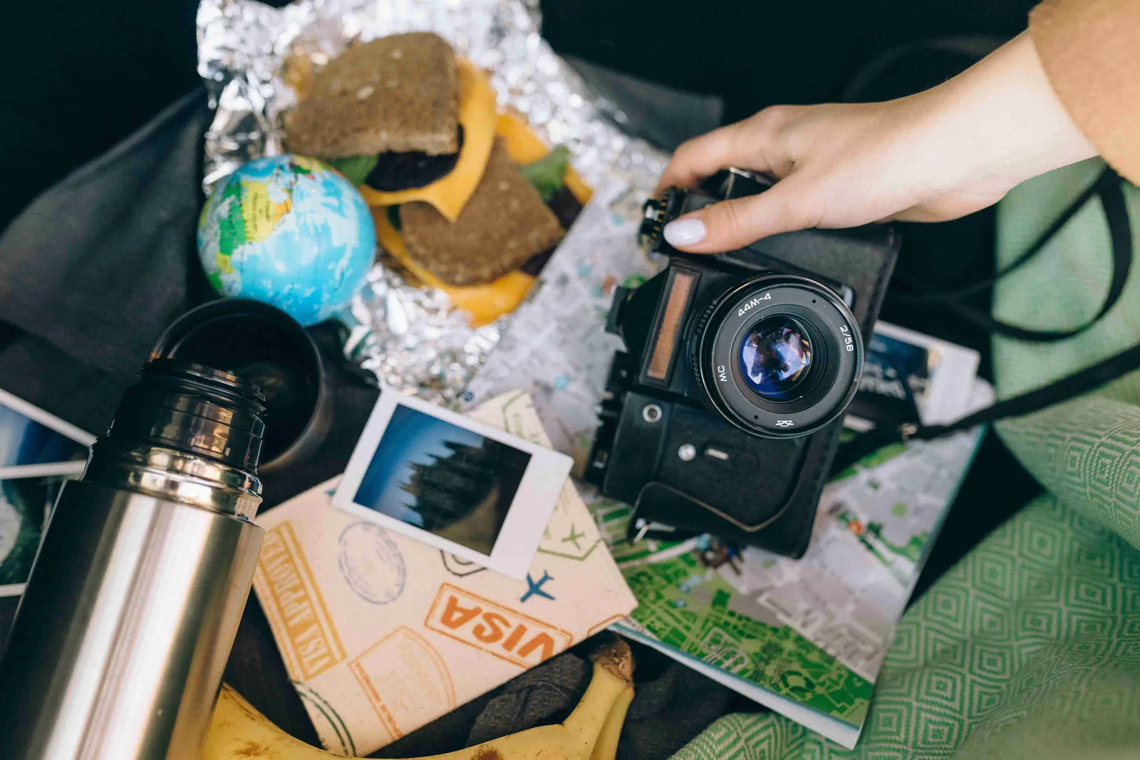 Travel accessories, camera, snacks, and a map laid out for a trip