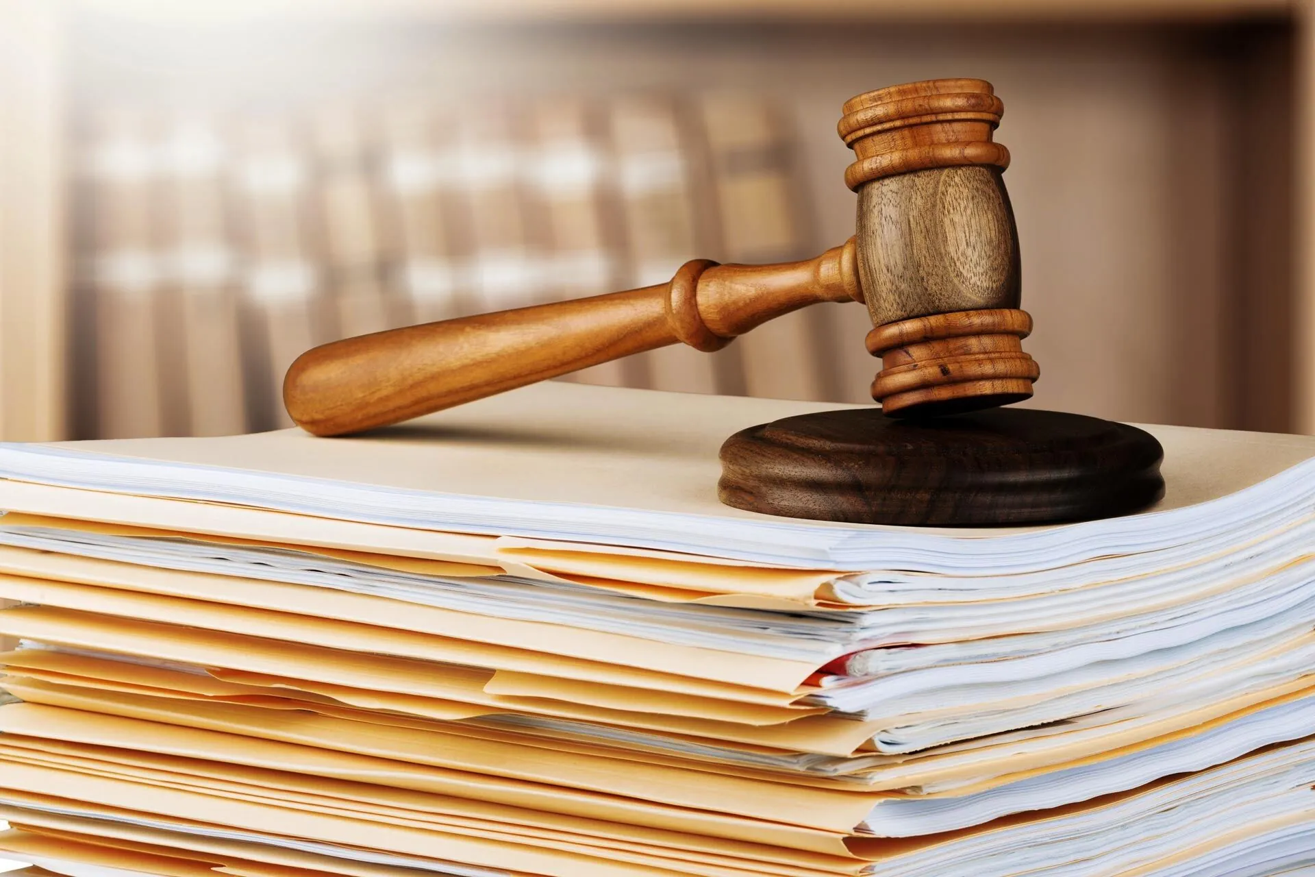A wooden judicial gavel sitting on a stack of legal documentation